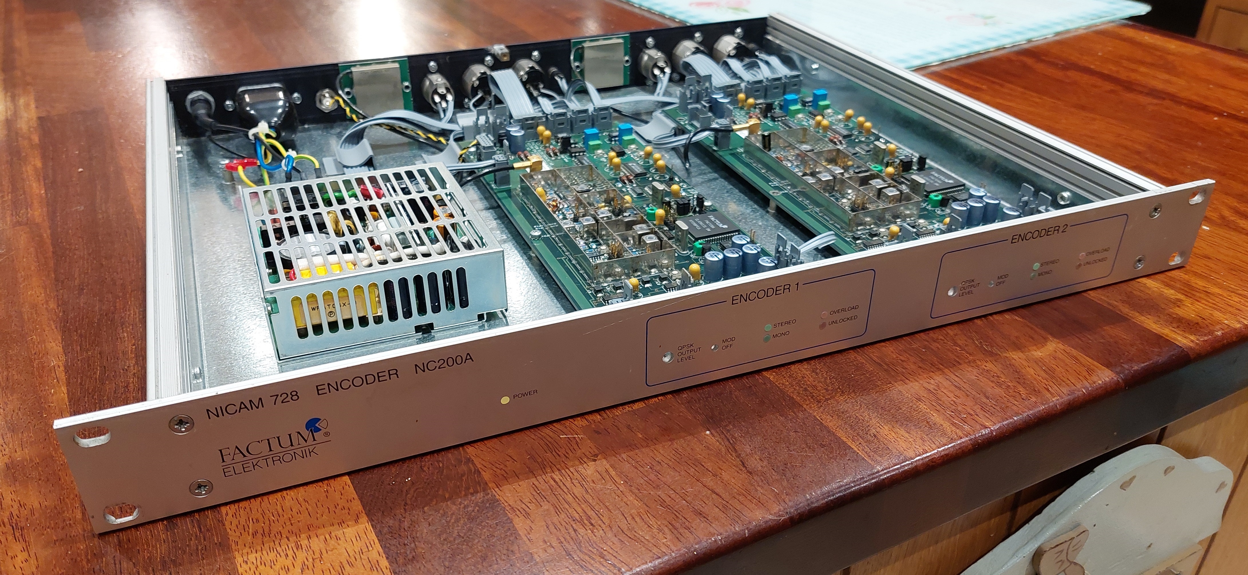The NC200A unit. It's a 1U rack mountable design with a silver finish and screen-printed labels. Removing the cover reveals two medium sized circuit boards littered with surface mount componenets and a shielded power supply module.
